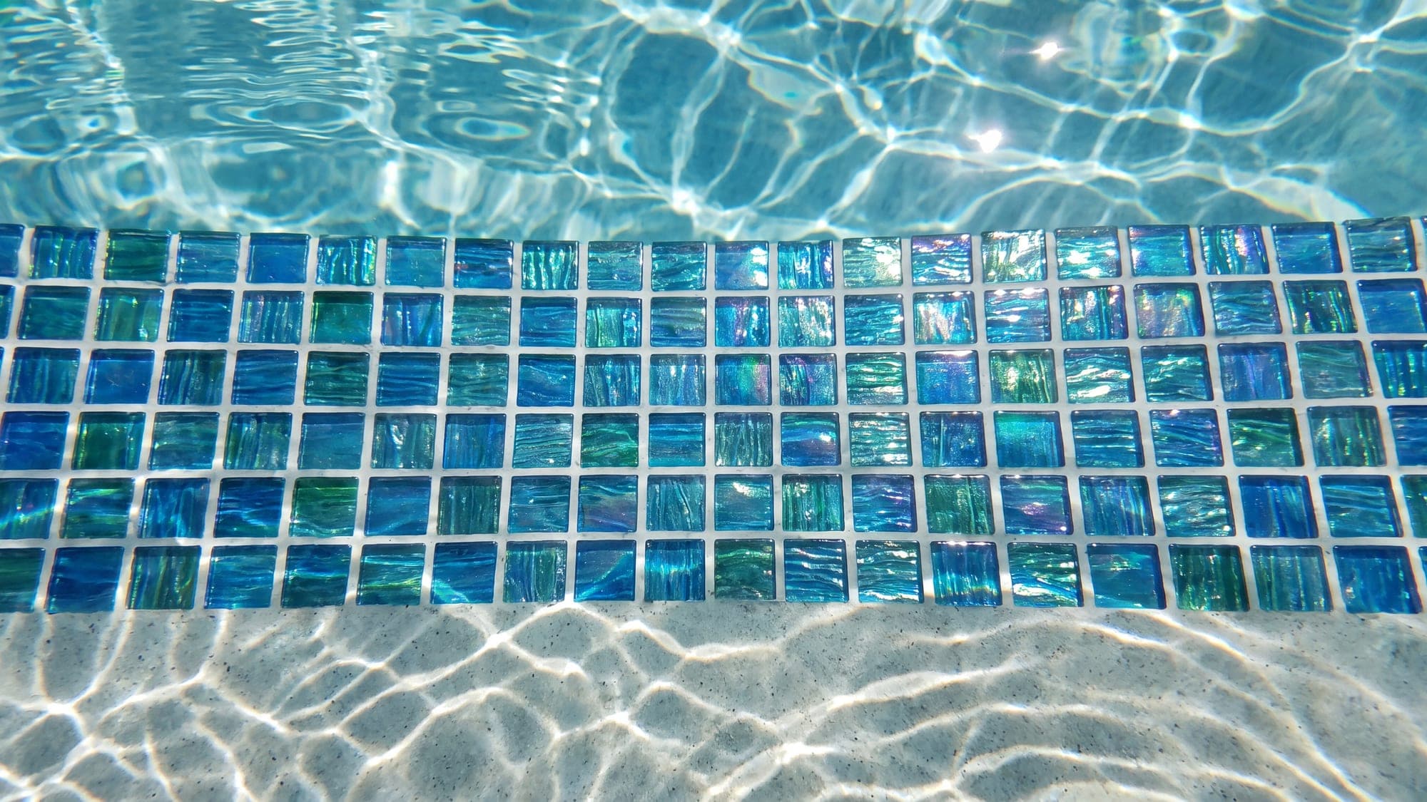 A perfectly aligned grid of glass mosaic tiles below the waterline.