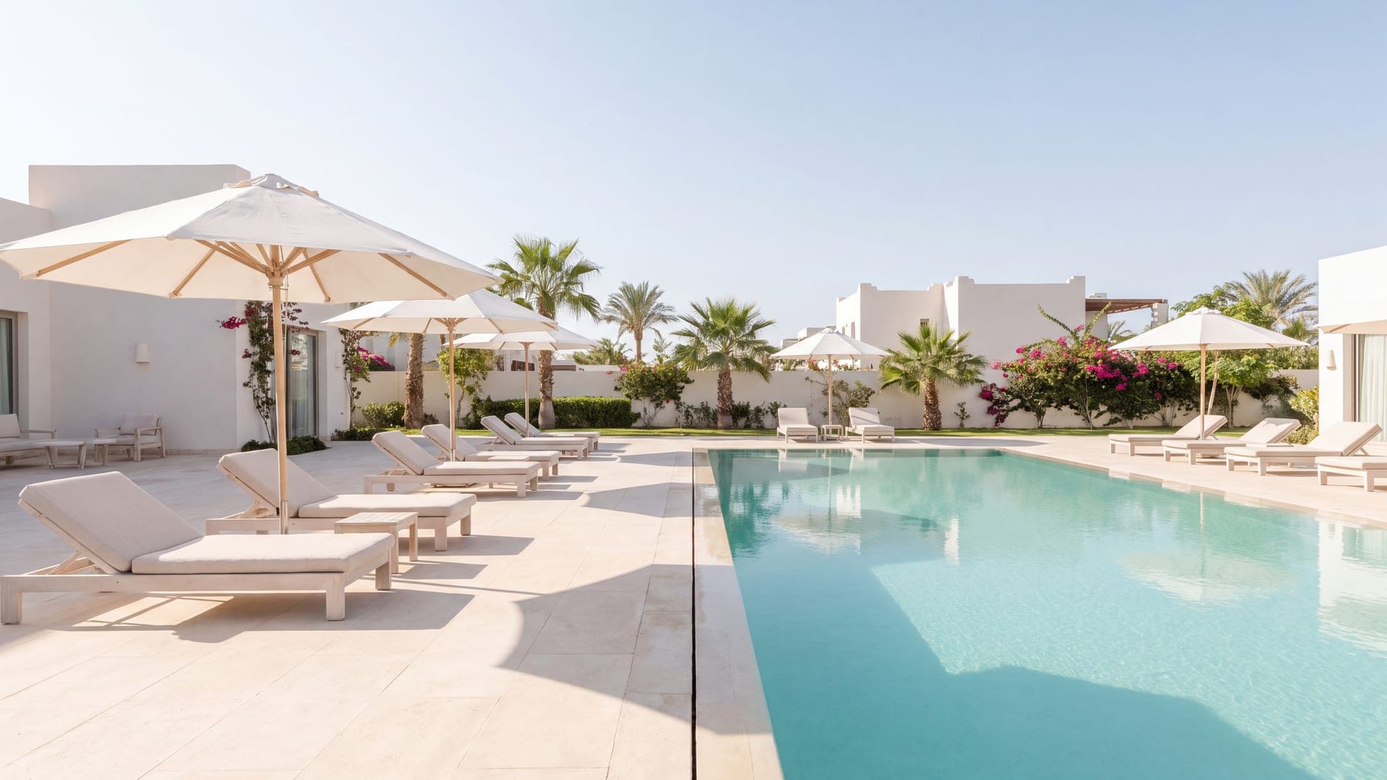 A bright modern pool on a clear morning, pale deck and turquoise water.